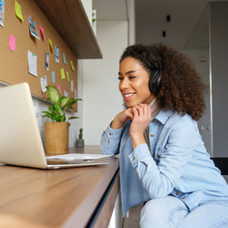 Smiling young woman wearing headphones and watching a webinar or doing video chat by webcam. Laptop Lifespan Concept.