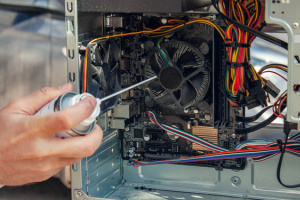 A person uses a compressed air cylinder to maintain and clean the computer's interior.