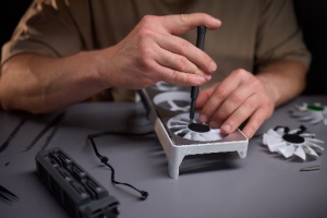 A skilled technician uses precision tools to repair a computer GPU fan, demonstrating expertise in GPU repair services and electronics.